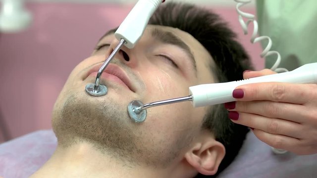 Microcurrent treatment close up. Young male face, cosmetology.