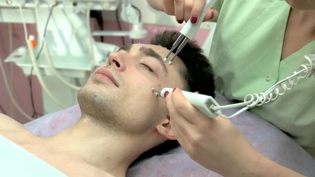 Microcurrent therapy device, male face. Caucasian man, cosmetology procedure.