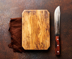 Wooden board with knife and on concrete brown table with copy space for design.