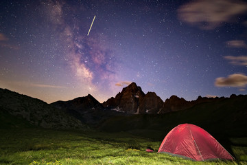 Camping under starry sky and milky way at high altitude on the Alps. Illuminated tent in the...