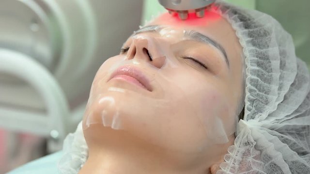 Female face, rf skin tightening. Young woman in facial mask.