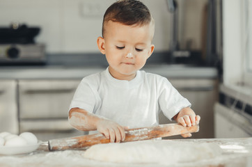 A child with a rolling pin at the table