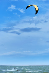 Man riding a kite surfing on the waves in the summer.