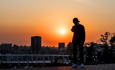 Fototapeta premium Silhouette of a young man on sunset background