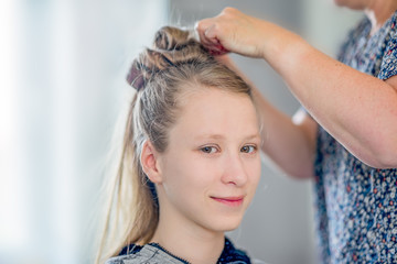 ein junges, blondes Mädchen zur Vorbereitung von Jugendweihe / Konfirmation beim Friseur / Hairstyler