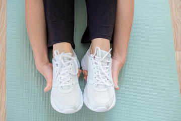Closeup of female hands covering white sneakers