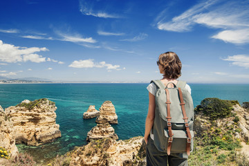 Female traveler looking at the sea in Lagos town, Algarve region, Portugal. Travel and active...