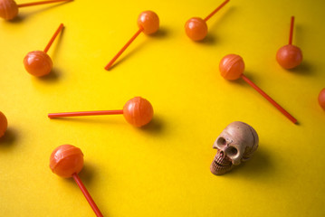 dessert lollipop on yellow ground with skull in halloween party concept