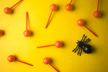 dessert lollipop on yellow ground with black spider in halloween party concept