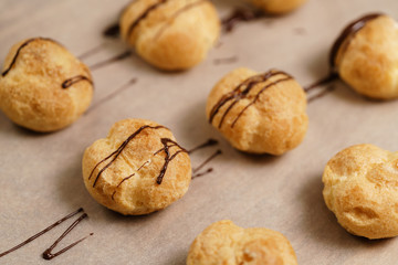 profiteroles decorated with dark chocolate on brown paper closeup