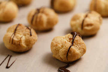 profiteroles decorated with dark chocolate on brown paper closeup