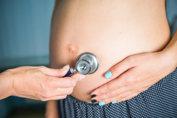 Fototapeta premium A family doctor listens with a phonendoscope for breathing, a pregnant heartbeat, a health check