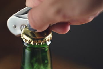 closeup young female hand open green beer bottle