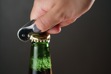 closeup young female hand open green beer bottle