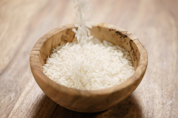 dry basmati rice fall in wood bowl on table