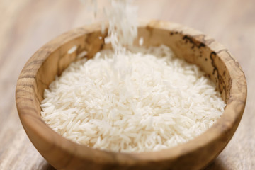 dry basmati rice fall in wood bowl on table