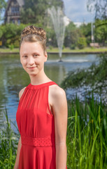junges, hübsches Mädchen im Sommer mit Hochsteckrisur und rotem Sommerkleid beim Fotoshooting zur...