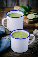 homemade green zucchini cream soup with parsley in mugs