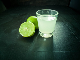 Fresh lime and lime juice on dark wooden table. Healthy concept.