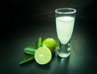 Fresh lime and lime juice on dark wooden table. Healthy concept.