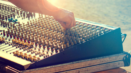 live sound mixing, a monitor engineer and console at an outdoor event (detail of hands controlling buttons)
