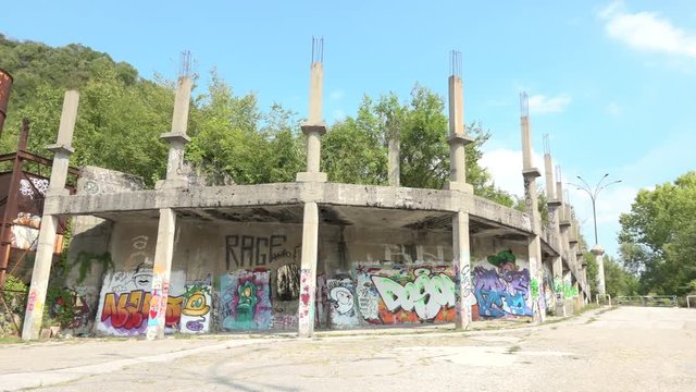 Abandoned silo and construction site with murals in Consonno, Italy. Rusted concrete tank and unfinished building with graffiti in dead town, desolate and scary place