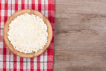 Cottage cheese in a wooden bowl on old wooden background with copy space for your text. Top view