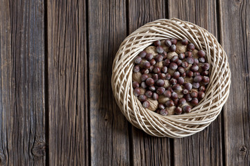 Walnuts and hazelnuts in  decorative wicker circle on rustic wooden vintage background. Top view, background, decor, space for your text. Autumn concept in  rural style.