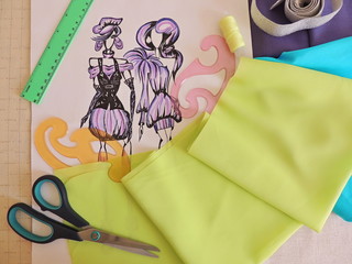 Sewing accessories and fashion sketches of clothing on the desktop
