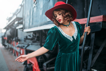 Obraz na płótnie Canvas Woman in red hat on vintage steam locomotive