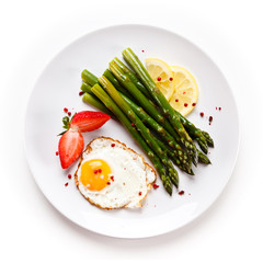 Fried egg with asparagus on white background 