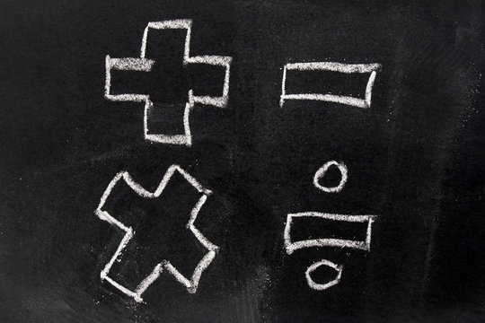 White chalk drawing in basic mathematics symbol (plus minus multiply divide) on black board background