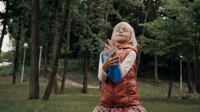 The little cheerful blond girl smiling and catching a piece of a plastic shaped like a plate as a game. Slow motion. HD