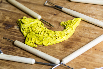 Figurine clay plasticine in a workshop with tools on a wooden background