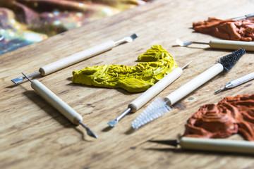 Figurine clay plasticine in a workshop with tools on a wooden background
