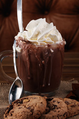 A messy cup with hot chocolate and chocolate chip cookies.