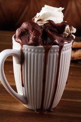 A messy cup with hot chocolate and chocolate chip cookies.