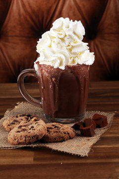 A messy cup with hot chocolate and chocolate chip cookies.