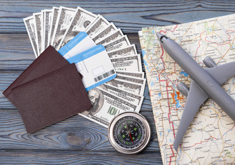 concept for a trip. card and an airplane, a passport with tickets. dollar banknote. On the background of a wooden table. Trip, flight, tourism, travel.
