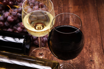 Red Wine bottle and white wine with grapes and glasses on wooden background