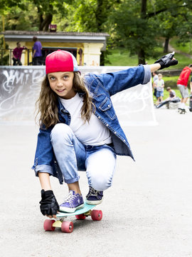 Cute girl in a baseball cap with a skateboard in a skate park. Sports.