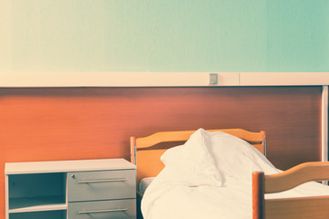 A bedside table stands near the empty hospital bed