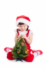 Little asian cute girl wearing santa dress sitting on the floor with christmas tree