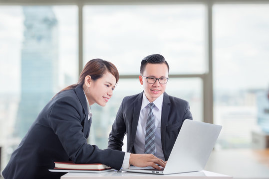 Young asian businessman and businesswoman discussing about work in office