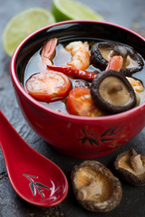 Close-up of a red bowl with spicy Tom Yum soup, selective focus, vertical shot