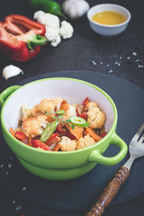 Vegetable stew of cauliflower, carrots and Bell peppers on a black background
