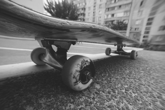 Close up of skateboard on the city road. Extreme sport challenge and skateboarder training, urban lifestyle, black-and-white picture