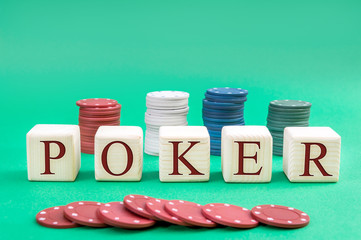 Wooden cubes with word "POKER" and poker chips on a green background.