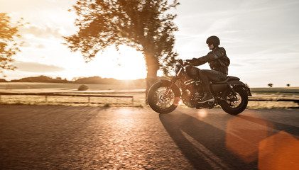 Man riding sportster motorcycle during sunset.