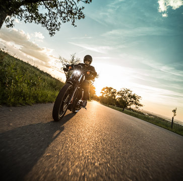 Man riding sportster motorcycle during sunset.